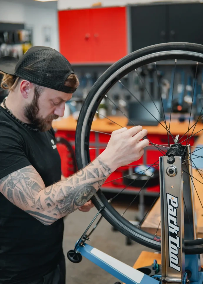 Ein Refresh Mitarbeiter prüft die Speichen an einem Laufrad.